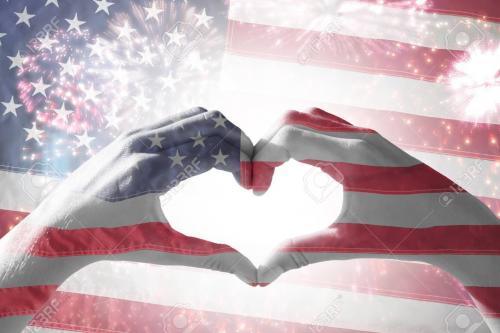 83959987-hands-making-heart-shape-on-the-beach-against-american-national-flag-with-stars-and-stripes