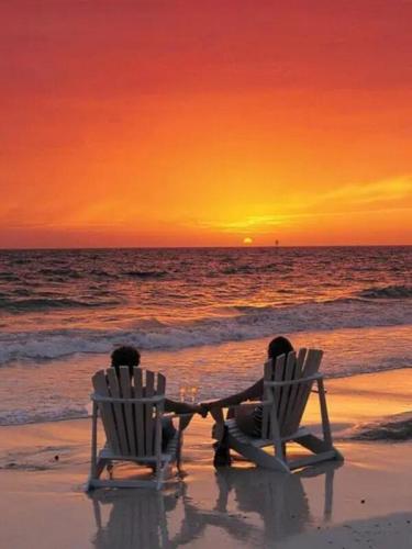 Couple watching beach sunset in chairs