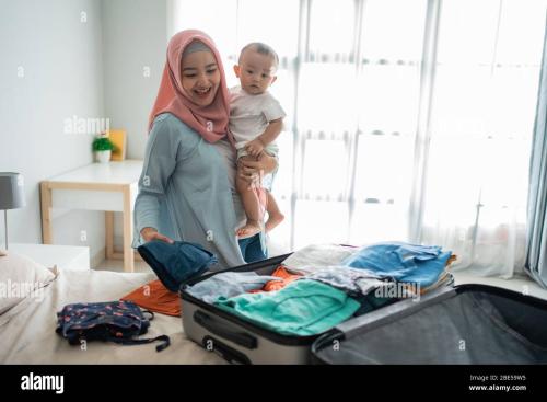 muslim-asian-mothers-carry-their-children-while-preparing-clothes-to-put-in-their-suitcases-before-traveling-2BE59W5