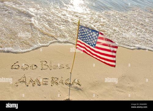 god-bless-america-text-in-beach-sand-with-an-american-flag-on-sunshine-2RA6WRC
