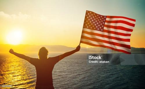 patriotic-man-waving-the-american-flag-against-sunrise