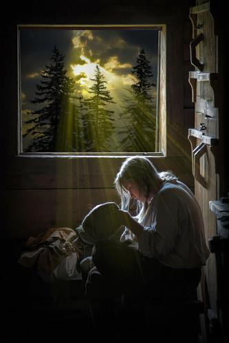 a-woman-is-illuminated-by-sunlight-streaming-through-the-window-as-she-sews-inside-a-wooden-cabin-randall-nyhof